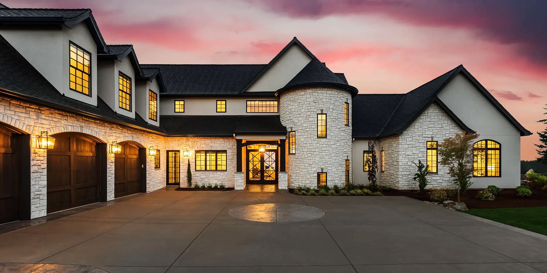 New luxury home with three car garage, large driveway and glowing exterior and interior lights